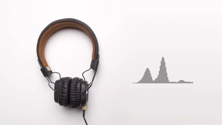 Black over-ear headphones resting on a white surface next to a digital soundwave visualization.